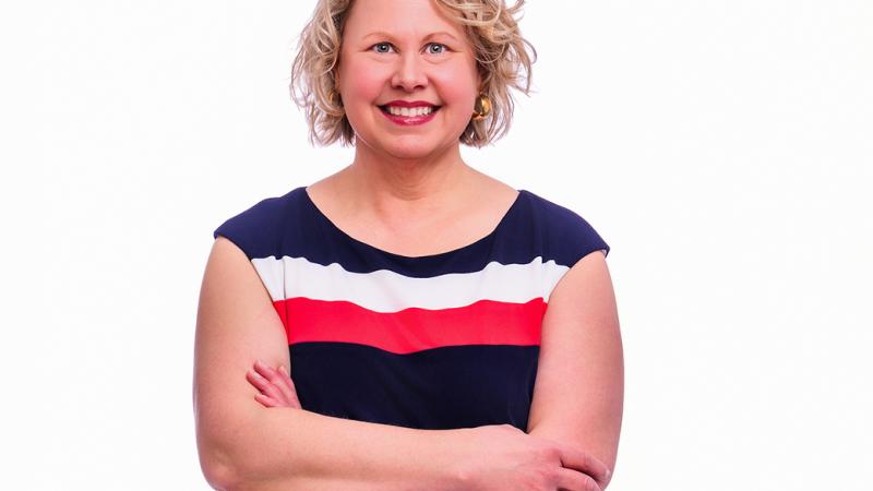 A photo of a woman, smiling with her arms crossed.