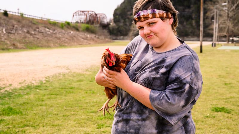 A photo of Caitlynn holding a chicken.