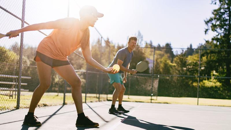 People outdoors playing pickleball. 