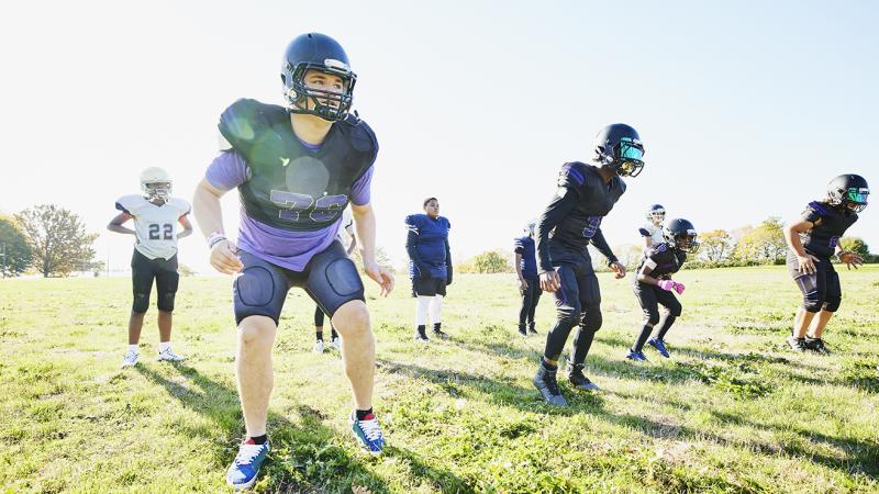 Students outdoors at football practice.
