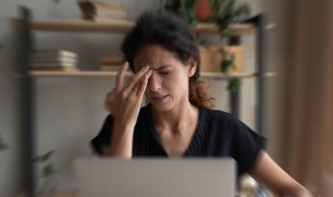 A woman applying pressure to her temple.