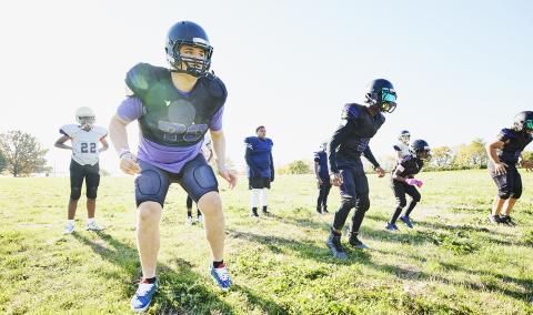 Students outdoors at football practice.